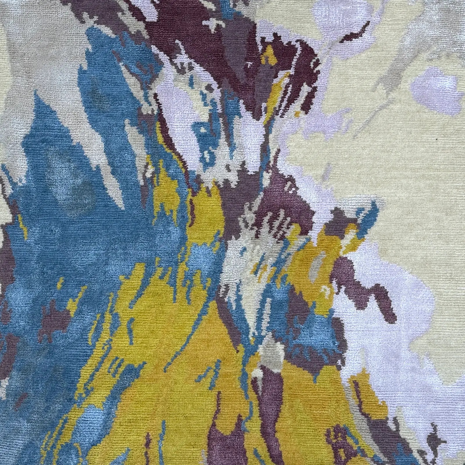 Abstract design of the Juno Autumn rug by Vaheed Taheri, featuring autumn colors of blue, yellow, and brown, showcasing high-quality hand-knotted craftsmanship.
